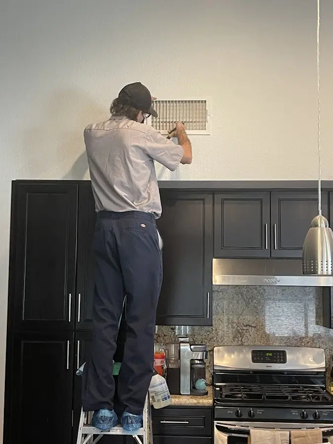 Technician inspecting an air vent during HVAC service in Shenango